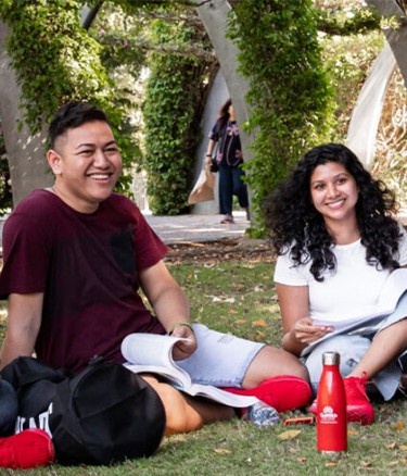 Five students sitting in college garden with books