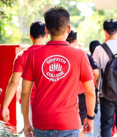 Group of students walking outside, two wearing red shirts.