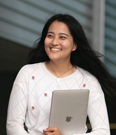Female student holding laptop and smiling