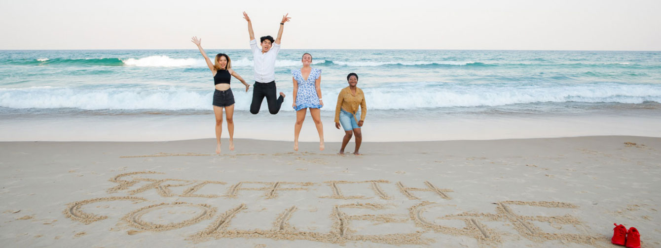 International students jumping beach
