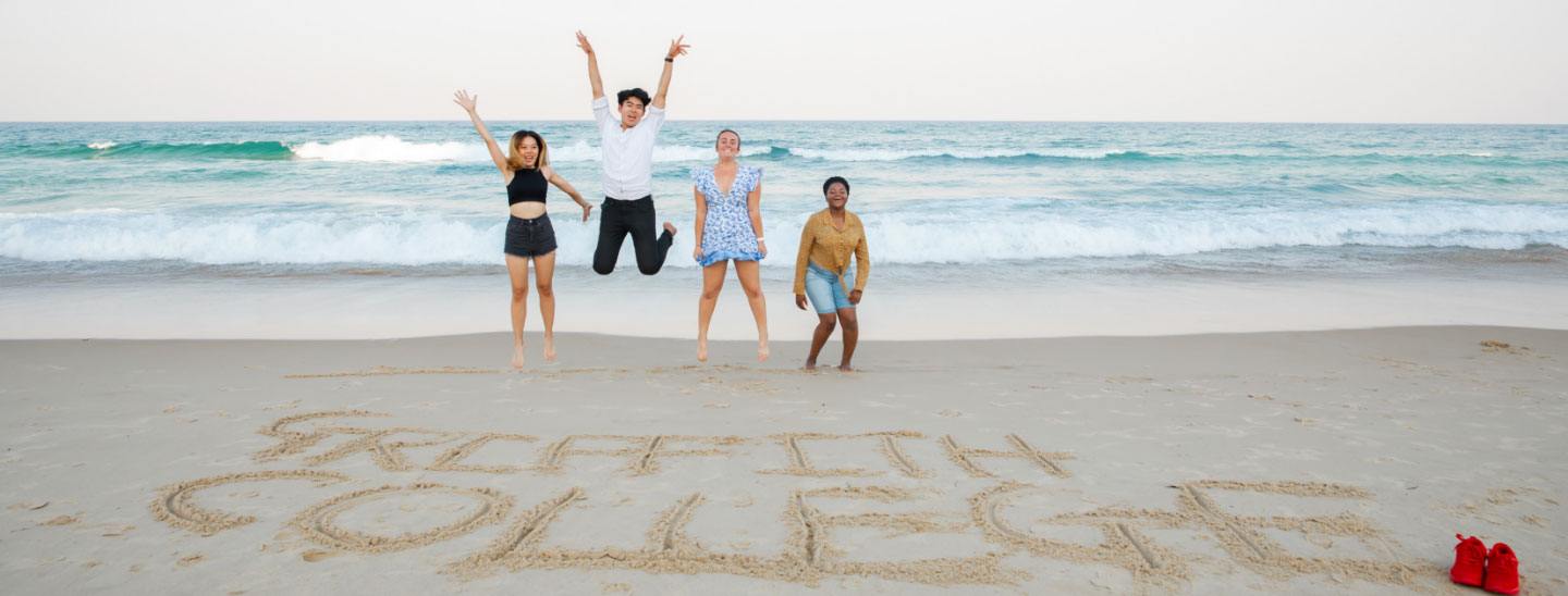 International students jumping beach