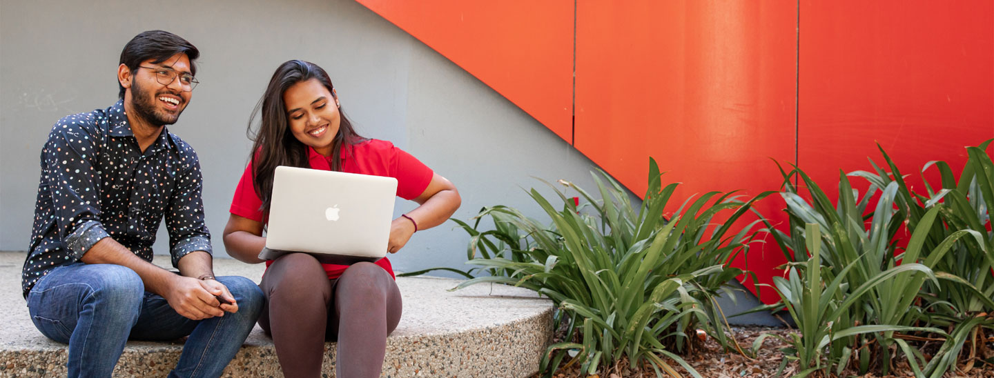 Male and female student sitting outside