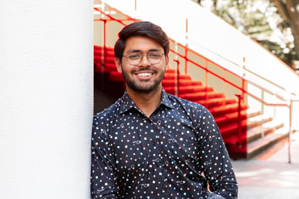 Male student standing against wall outside