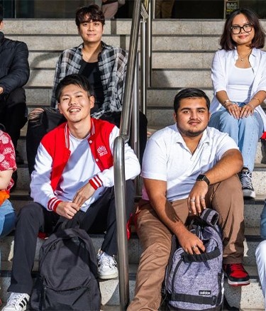Many students sitting on stairs with bags