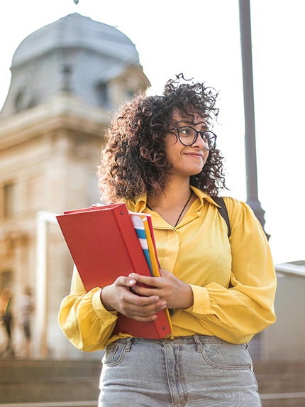 Female student holding file and walking outside