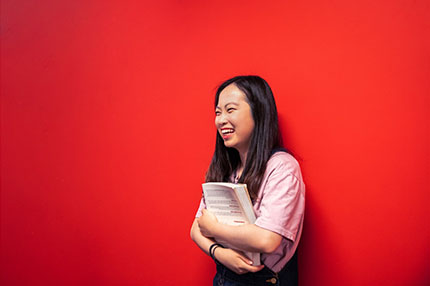Student happy red wall holding book