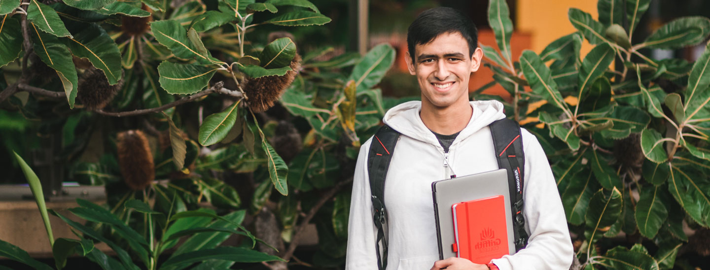 Student holding laptop and books