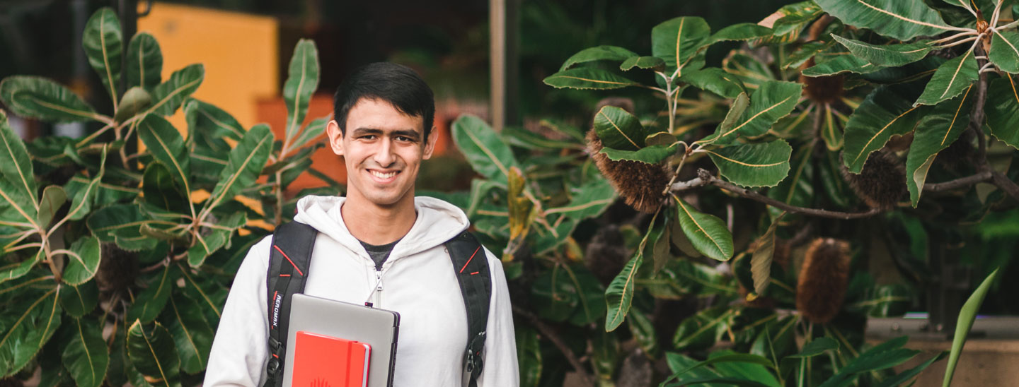 Student holding laptop and books