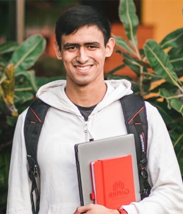 Student holding laptop and books