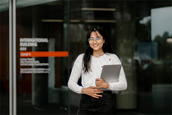Student outside building holding laptop