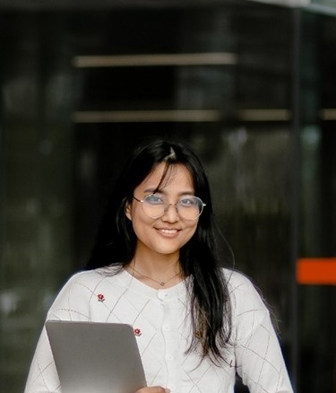 Student outside building holding laptop