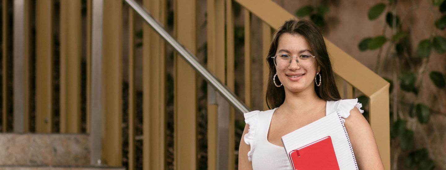 Student outside happy holding books