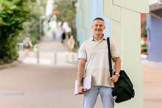 Student outside happy holding laptop