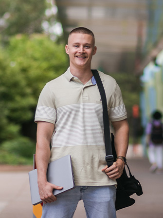 Student outside holding laptop