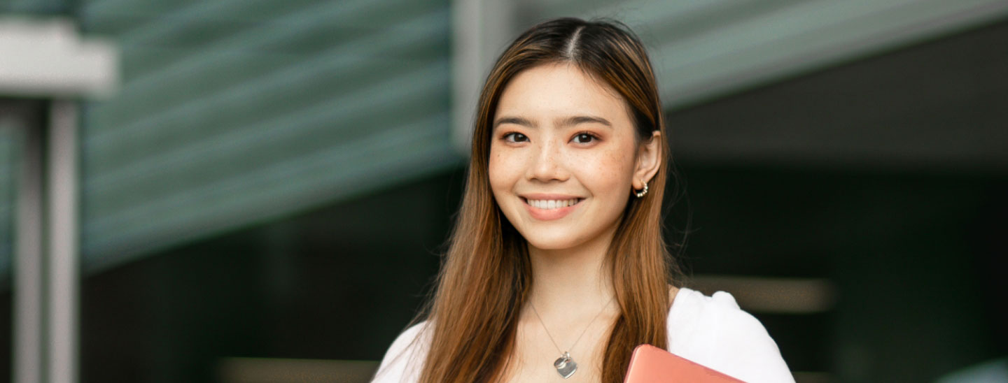 Student outside smiling holding documents