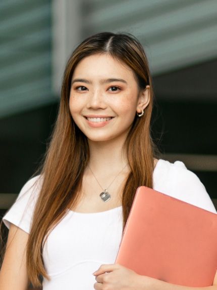 Student outside smiling holding documents