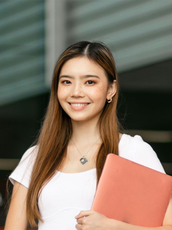 Student outside smiling holding documents