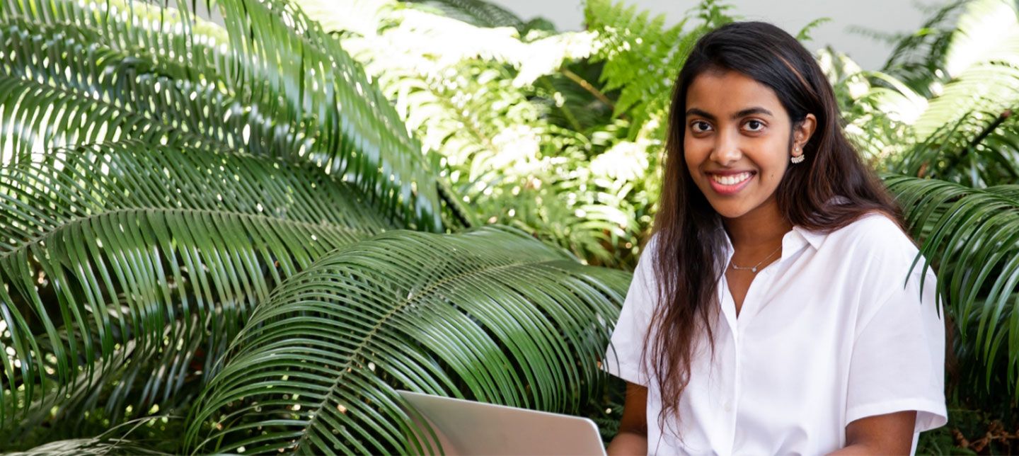 Student sitting outside laptop happy working