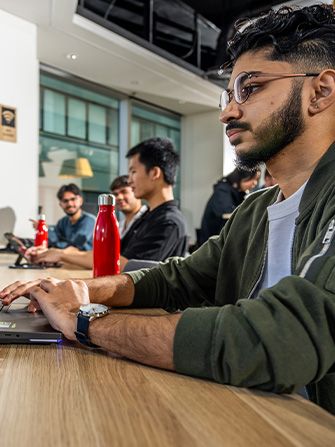 Male student typing on laptop keyboard
