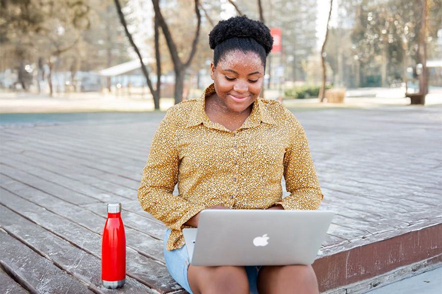 Female student working on laptop outside in the campus