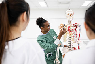 Students inside health lab human skeleton