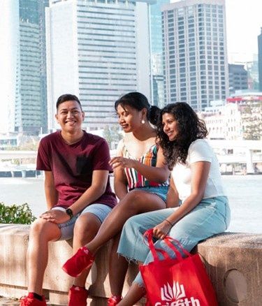 Three students sitting near water body